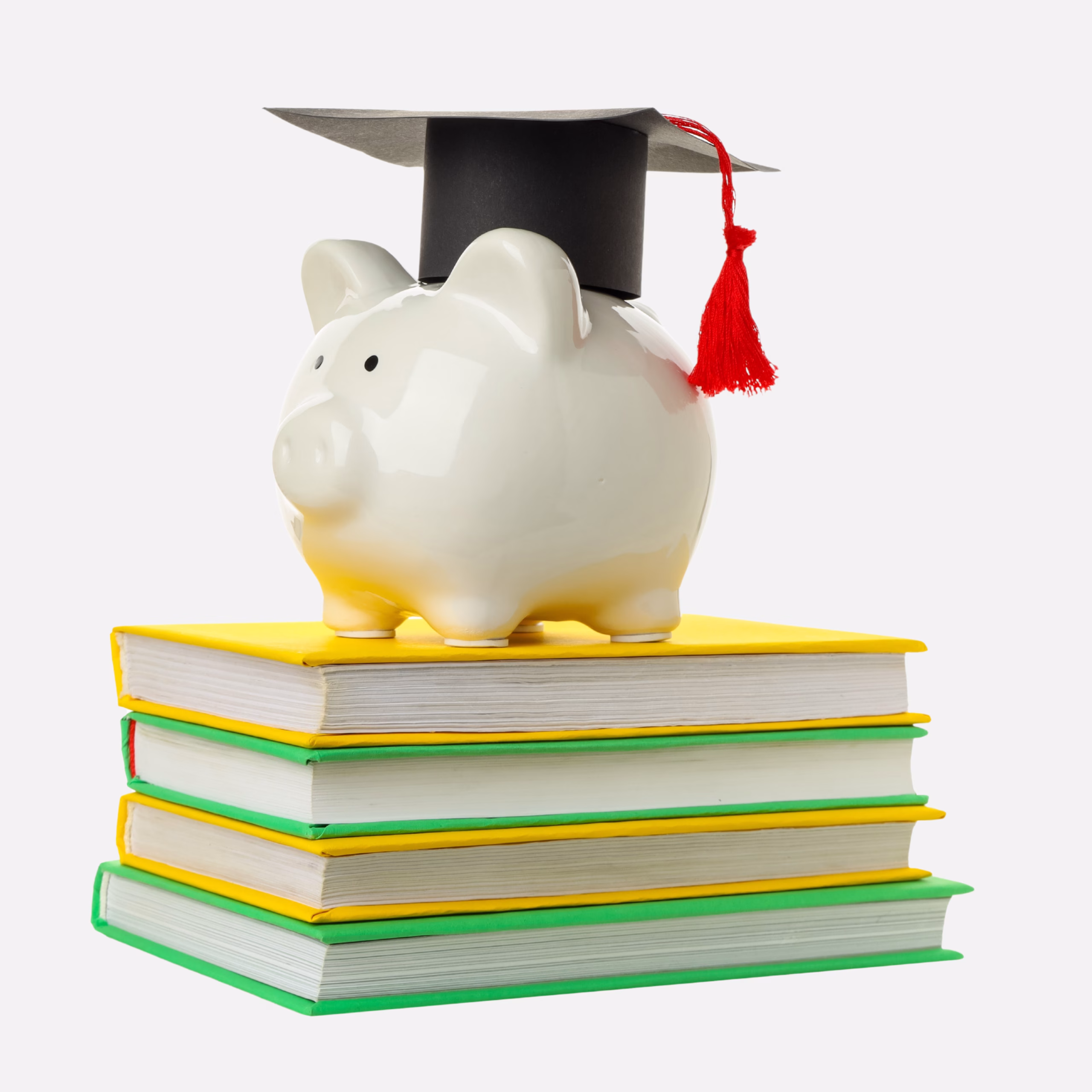 A white piggy bank wearing a graduation cap sits on top of a stack of four books with yellow and green covers, symbolizing education and saving money.